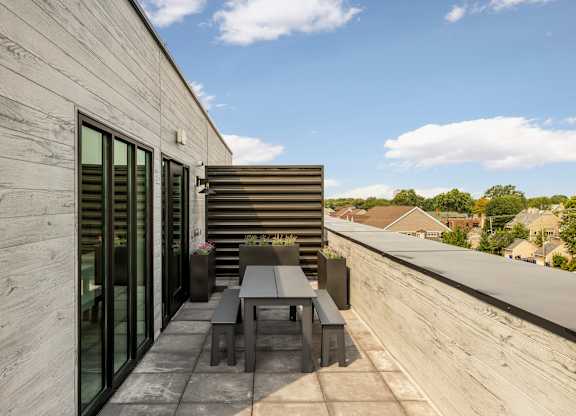 A modern balcony with a table and chairs overlooking a residential area.