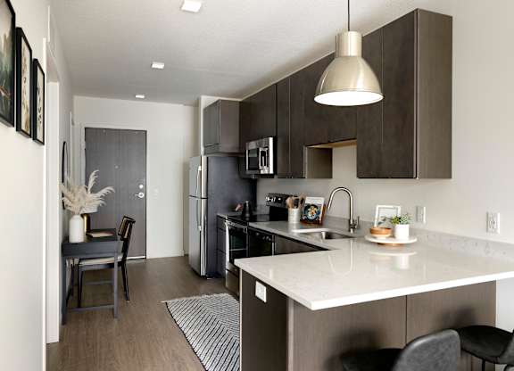 A kitchen with a white counter top and black chairs.