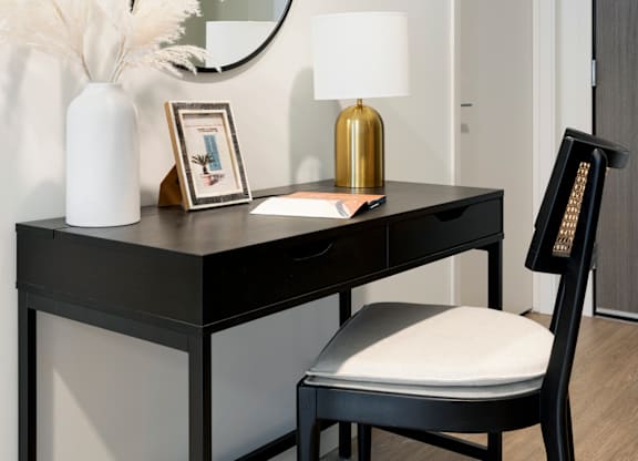 A black desk with a white chair and a round mirror above it.