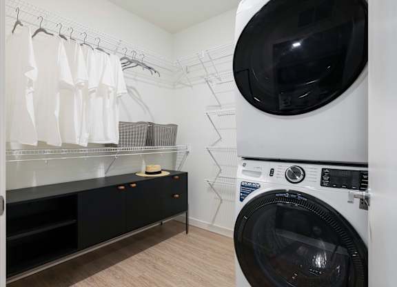 A washing machine is in a laundry room with a dryer in the background.