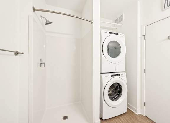 A white bathroom with a washer and dryer in it.