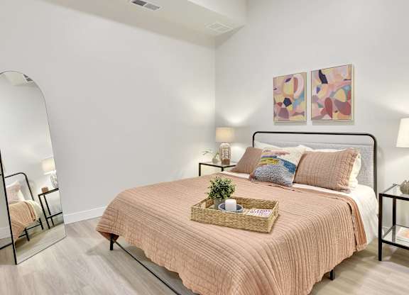 A bedroom with a bed, nightstand, and a painting on the wall.