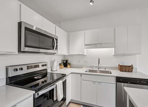 A modern kitchen with white cabinets and stainless steel appliances.
