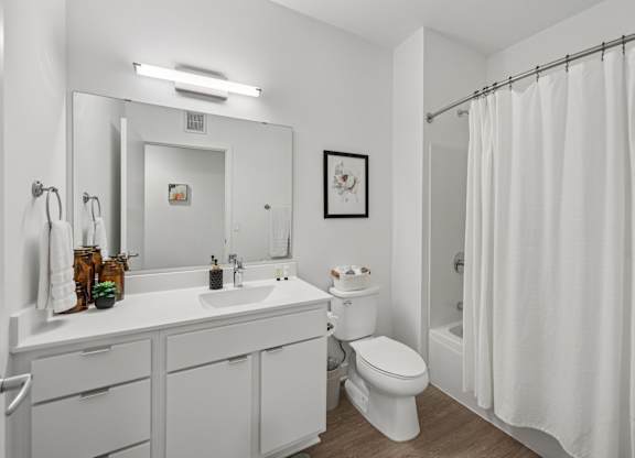 A white bathroom with a toilet, sink, and shower.