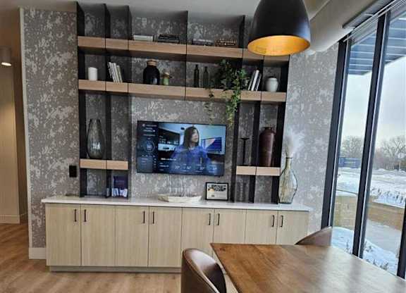 A modern living room with a wooden floor and a television on a cabinet.