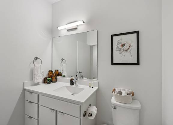 A white bathroom with a sink, toilet, and a mirror.
