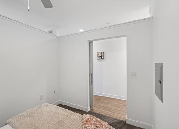 A bedroom with a bed and a door leading to another room.