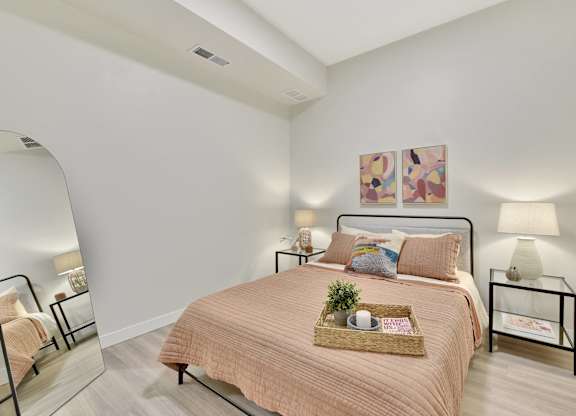 A bedroom with a bed, nightstand, and two wall lamps.