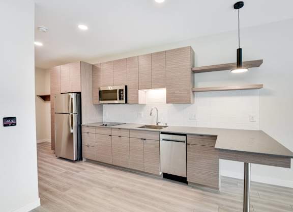 A modern kitchen with a refrigerator, microwave, and a countertop.