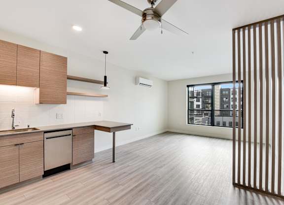 A modern kitchen with wooden cabinets and a ceiling fan.