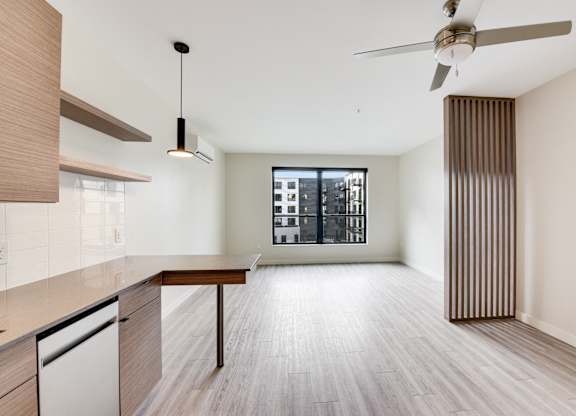 A modern kitchen with a wooden floor and a ceiling fan.