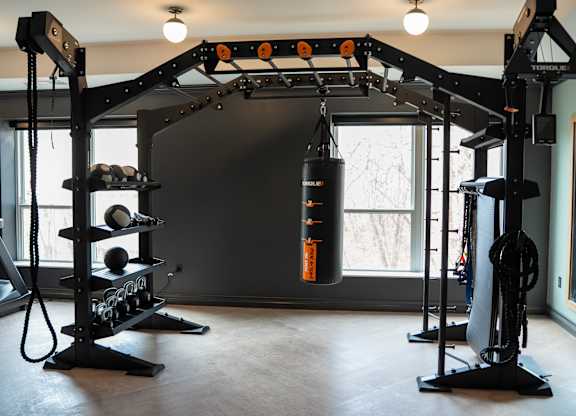 A home gym with a punching bag, weight rack, and a bench.
