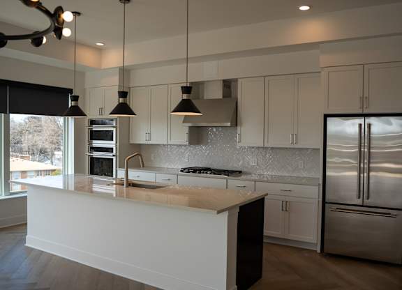A modern kitchen with a large island and stainless steel appliances.