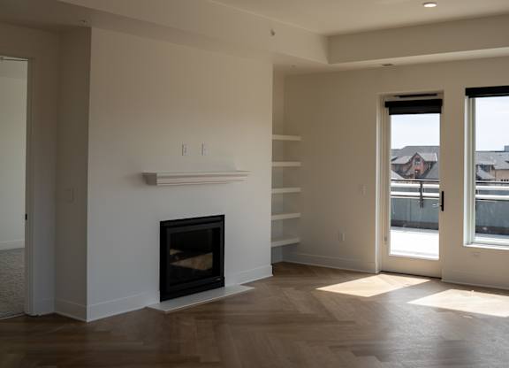 A modern living room with a fireplace and wood flooring.