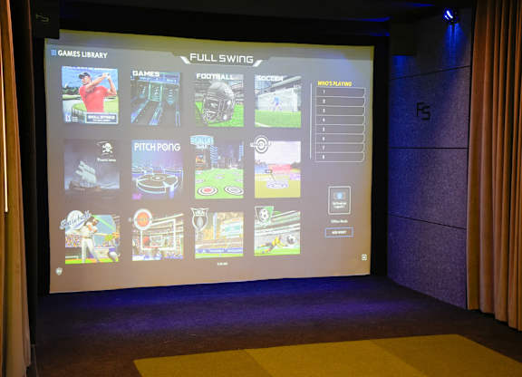 A screen displays a variety of video game options in a dark room.