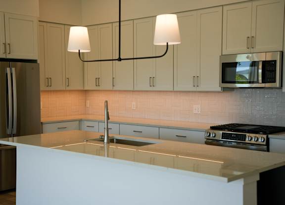 A kitchen with a white counter top and a microwave above it.