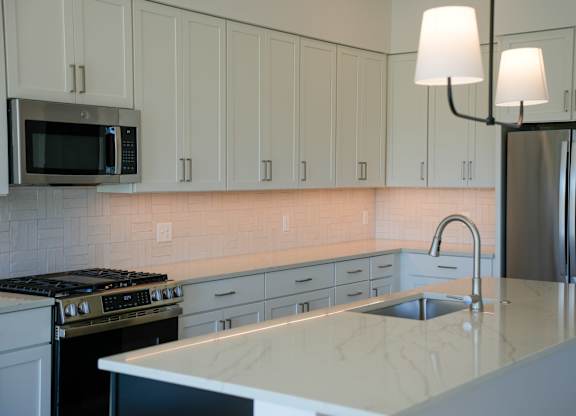 A kitchen with white cabinets and a marble countertop.