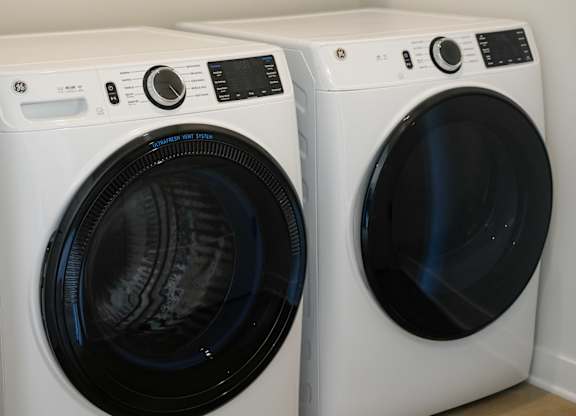Two white front load washing machines in a laundry room.