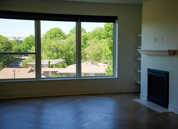 A large empty room with a fireplace and a view of the outdoors through the windows.