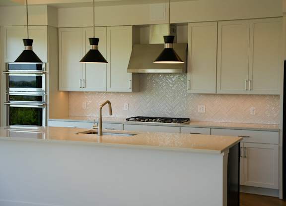 A kitchen with a white counter top and a black and silver range hood.