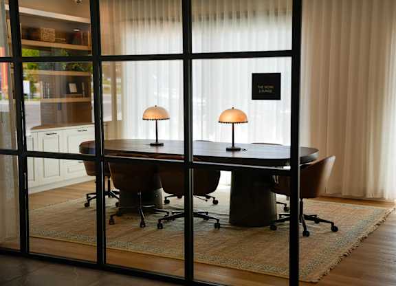 A conference room with a table, chairs and two lamps.