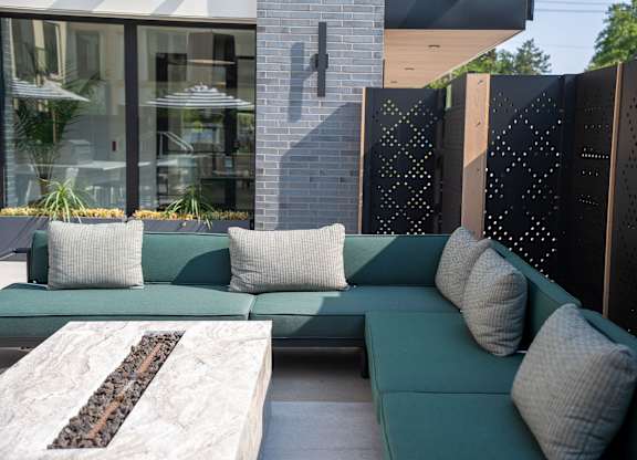 A modern outdoor seating area with a green couch and a stone coffee table.