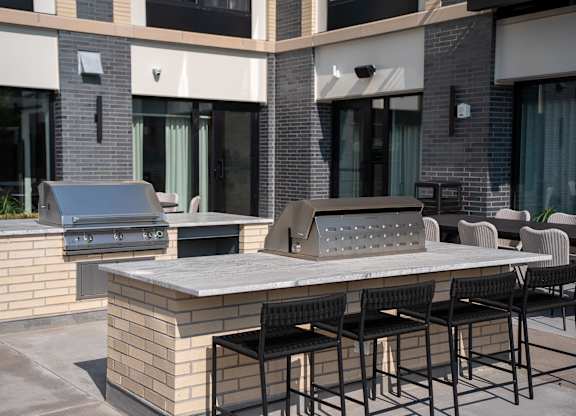 A patio with a table, chairs, and a grill.