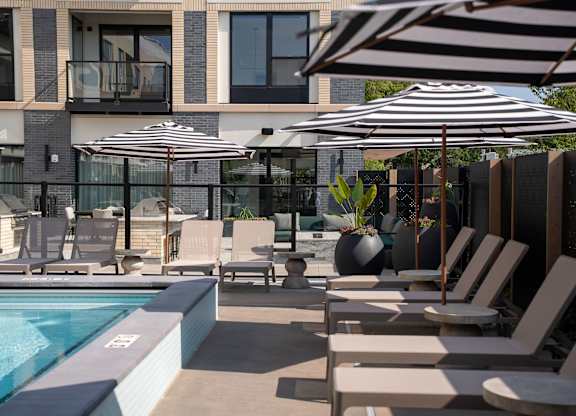 A pool area with sun loungers and umbrellas.