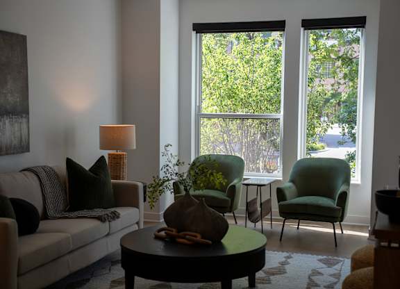 A living room with a couch, two chairs, a table, and a window.