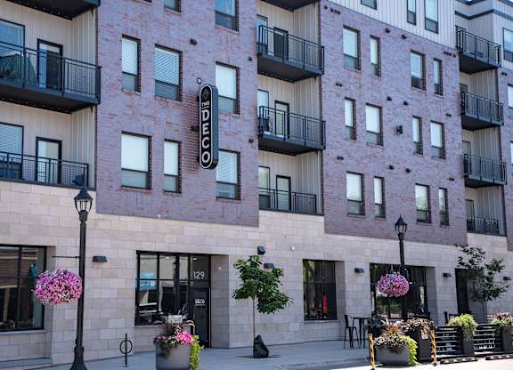 A building with balconies and flower pots in front.
