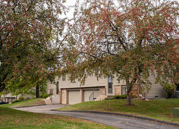 A tree with red leaves in front of a house.