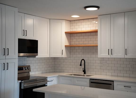 A kitchen with white cabinets and a black oven.