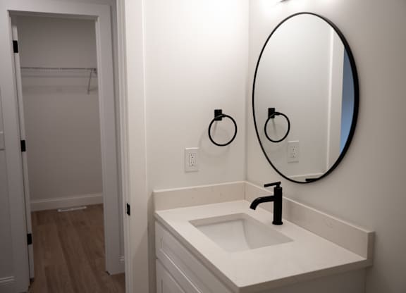 A bathroom sink with a round mirror above it.