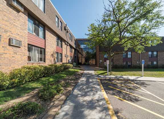 A street view of a residential area with apartment buildings and a parking lot.