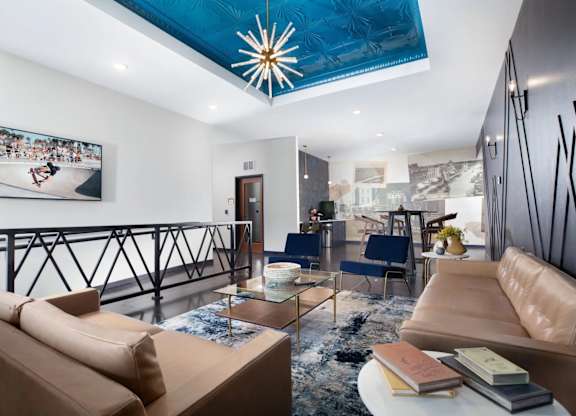 A living room with a tan sofa and a blue ceiling light.