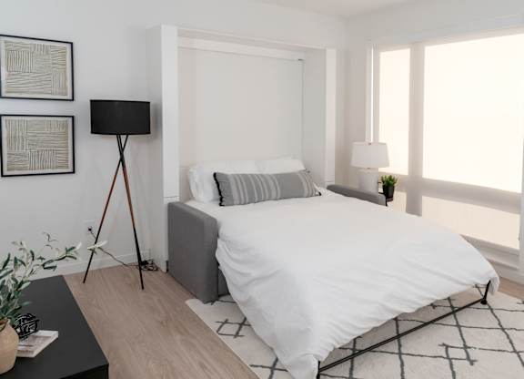 A bedroom with a white bed and a black floor lamp.