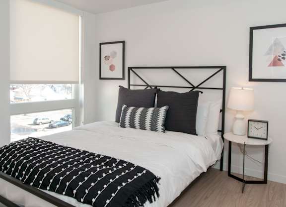 A bedroom with a white bed and black and white decor.