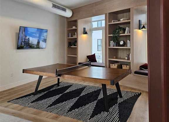 A modern living room with a wooden table and a TV mounted on the wall.