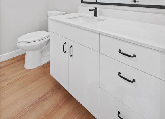A white bathroom with a toilet, sink, and mirror.