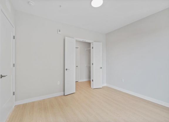 A room with white walls and a wooden floor with two doors.