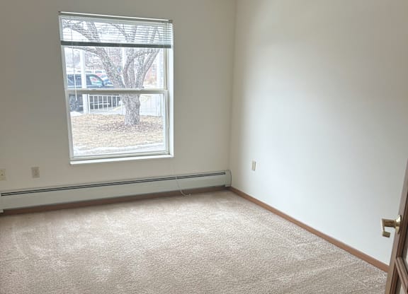 A room with a window and a car parked outside.