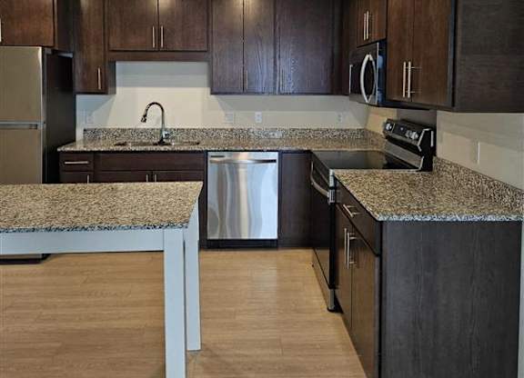 A kitchen with dark wood cabinets and a granite countertop.