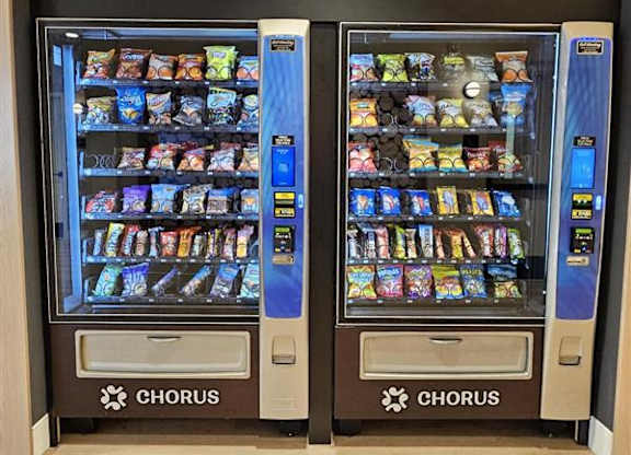 Two Chorus vending machines with a variety of snacks inside.
