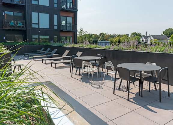 A patio with chairs and tables is in front of a building.