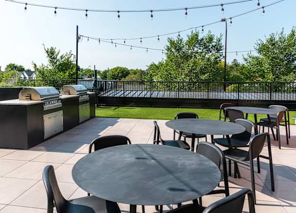 A patio with tables and chairs and string lights.