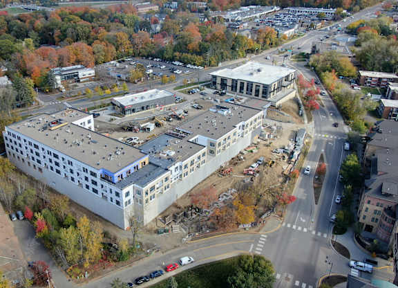 An aerial view of a large building surrounded by trees with autumn foliage.