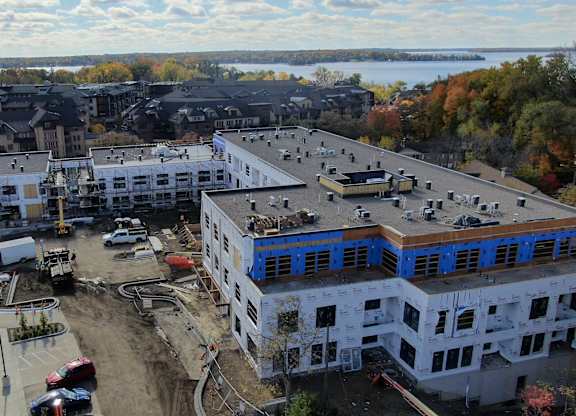 A construction site with a building under construction in the foreground and a row of houses in the background.