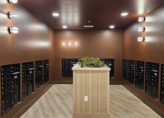 A room with a wooden floor and a long row of black cabinets on the wall.