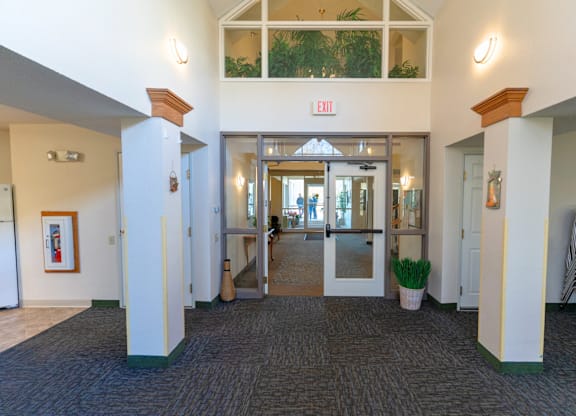 A hallway with a red exit sign above the door.