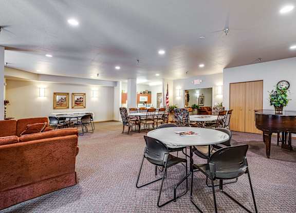 A room with a piano, chairs, and a dining table.